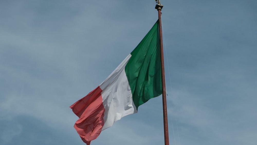 italian-flag-fluttering-against-blue-sky-SBI-351525636.jpg